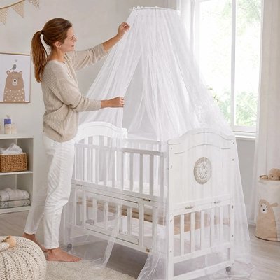 bébé moustiquaire blanc installé par une maman sur un berceau