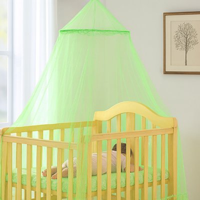 Ciel de lit bébé vert pomme au-dessus d'un lit en bois clair