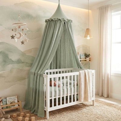 Ciel de lit vert enveloppant le berceau d'un bébé qui dort