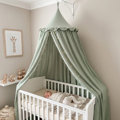 Ciel de lit vert fixé au mur au-dessus d'un bébé endormi