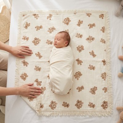 Couverture bébé motifs oursons à plat sous un nourrisson emmailloté