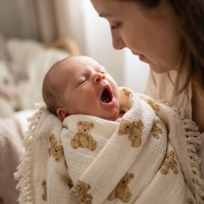 Couverture bébé motifs oursons enveloppant un nouveau-né qui bâille