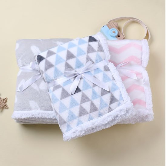 Couverture bébé naissance bleu ciel, rose et gris posé sur plancher