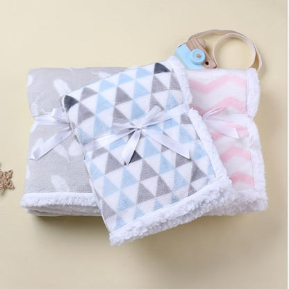 Couverture bébé naissance bleu ciel, rose et gris posé sur plancher