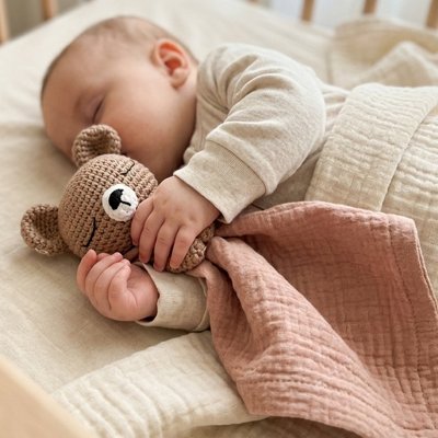 Doudou bébé brique en crochet serré par un nourrisson endormi.