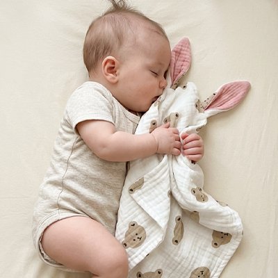 Doudou tête d'ourson câliné par un bébé endormi de profil