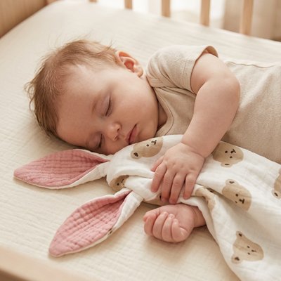 Doudou tête d'ourson serré contre un nourrisson qui fait la sieste
