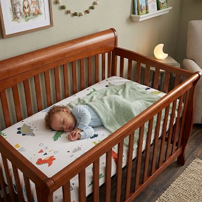 Drap housse lit bébé motifs dinosaures sous enfant assoupi sous couverture