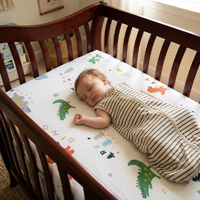 Drap housse lit bébé motifs dinosaures sous enfant assoupi