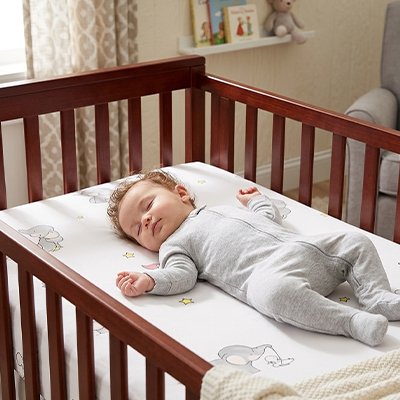Drap housse lit bébé motifs éléphants avec enfant couché sur le dos