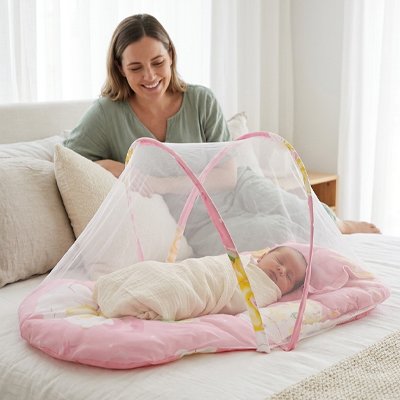 Lit moustiquaire bebe rose sieste avec maman assise au chevet