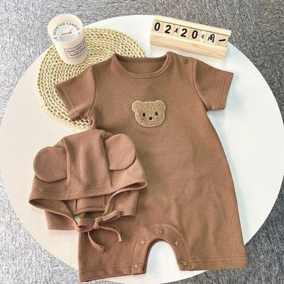 Pyjama bébé garçon chocolat avec bonnet à plat sur une table